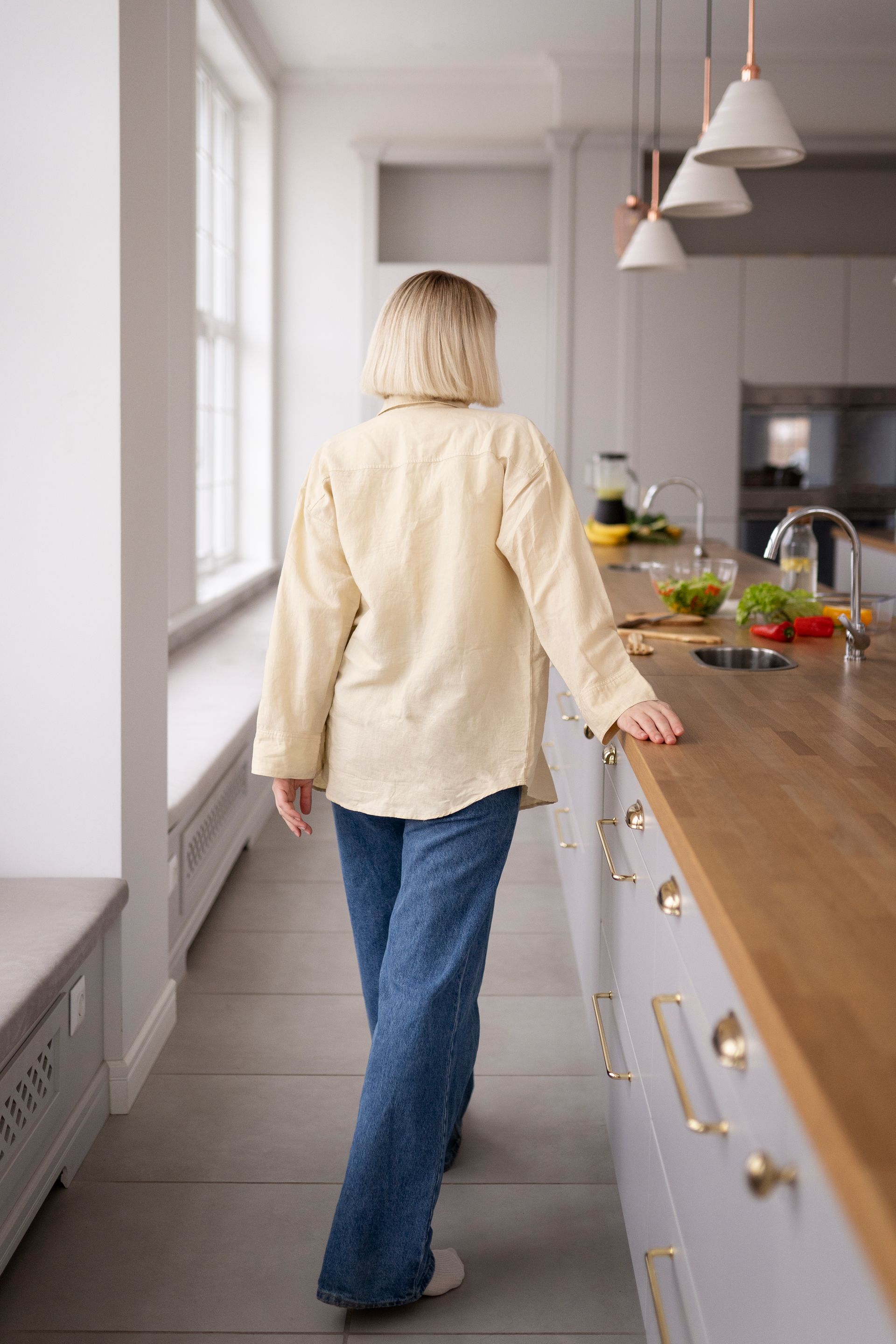 A woman is standing in a kitchen leaning on a counter.