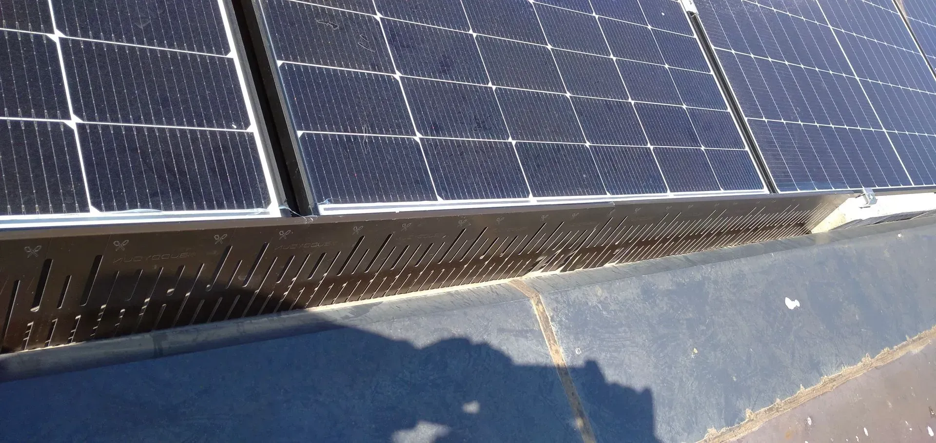 Primo piano di pannelli solari blu con striature bianche di neve lungo il bordo su un tetto.