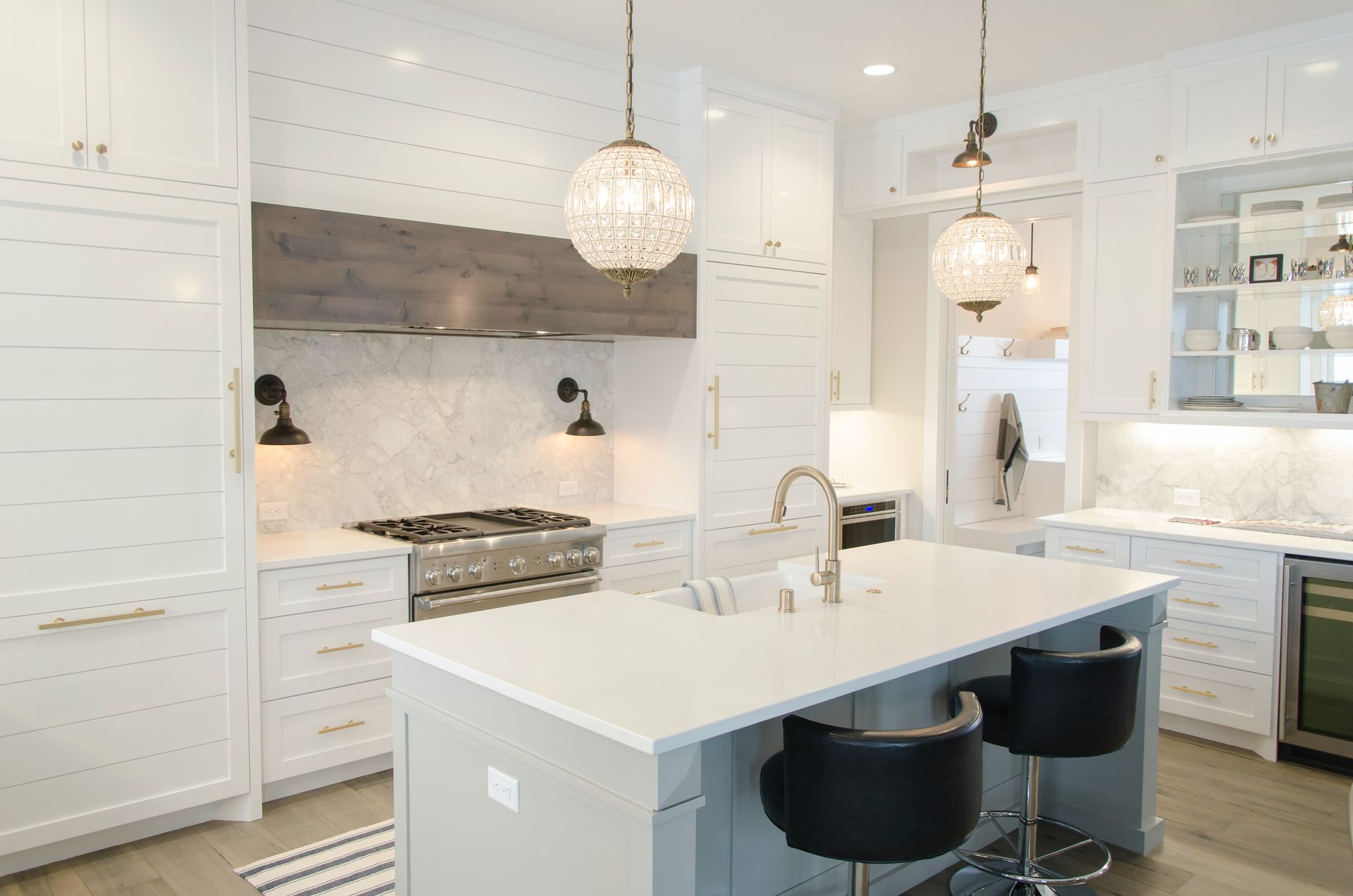 Modern white bathroom with patterned floor, double vanity, glass shower, and black fixtures.