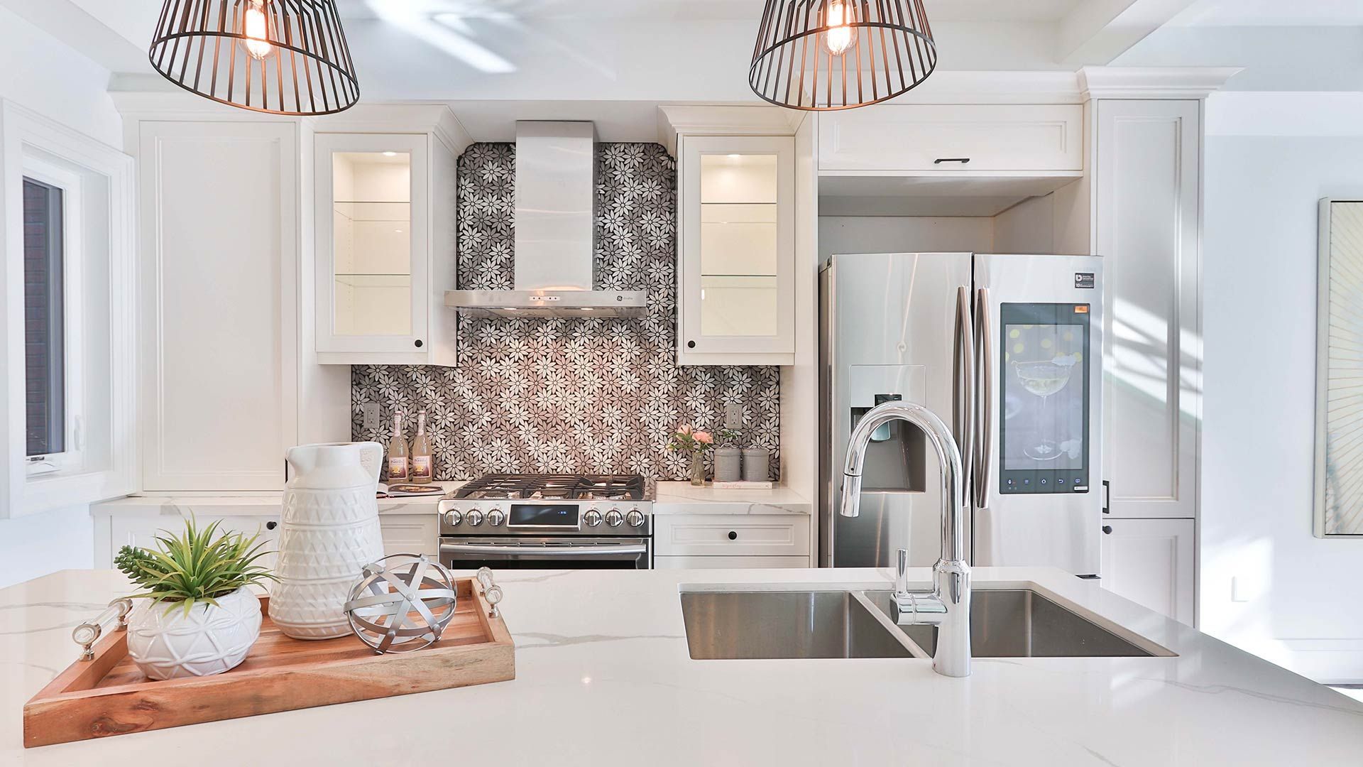 Bright, modern kitchen with white cabinets, stainless steel appliances, and a mosaic backsplash.