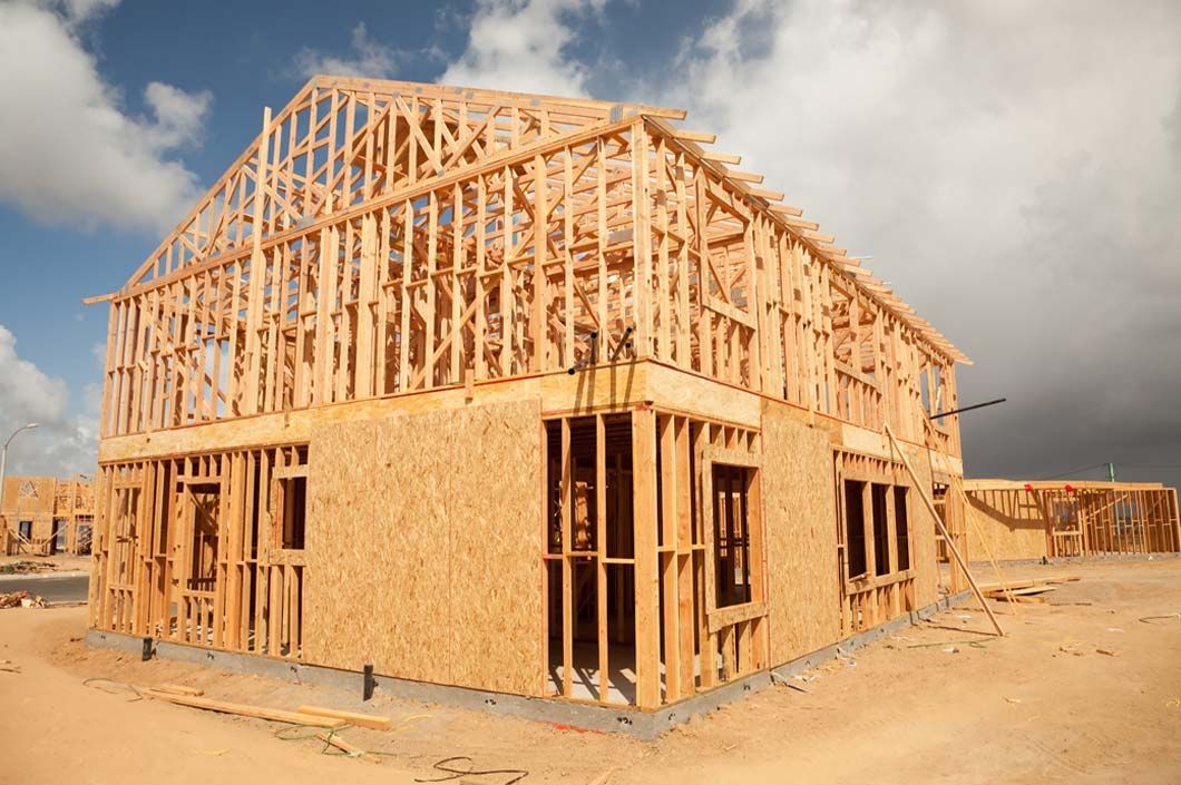 Dining room with wooden table, gray chairs, and industrial light fixture. Kitchen in the background.