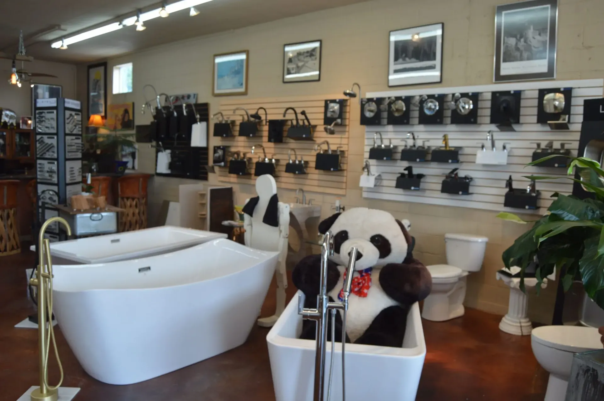 A teddy bear is sitting in a bathtub in a bathroom showroom.