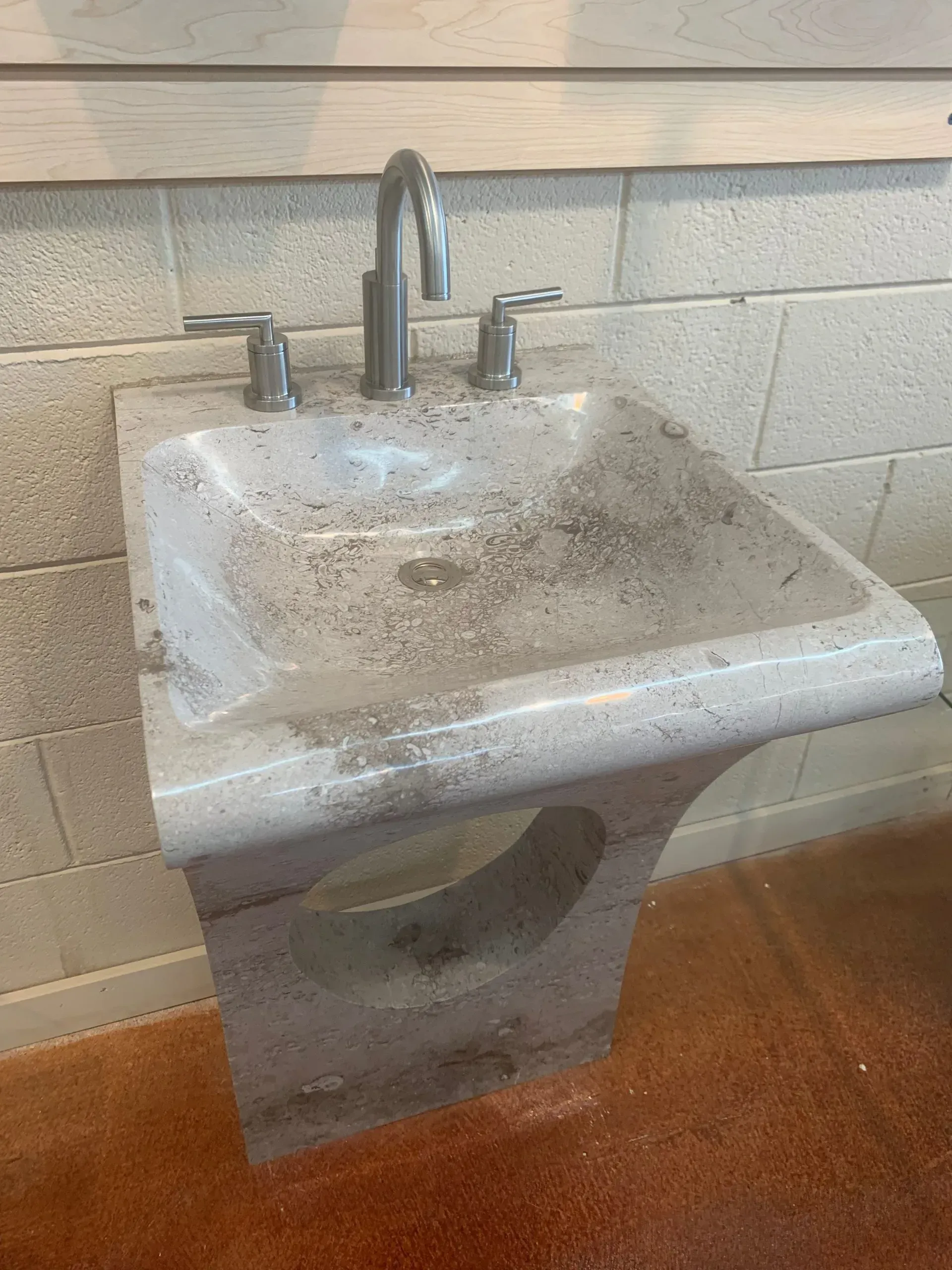 A dirty bathroom sink with a faucet on a brick wall.
