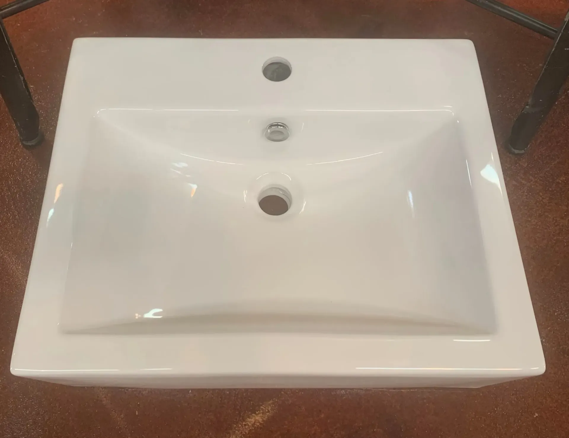 A white bathroom sink is sitting on top of a wooden table.