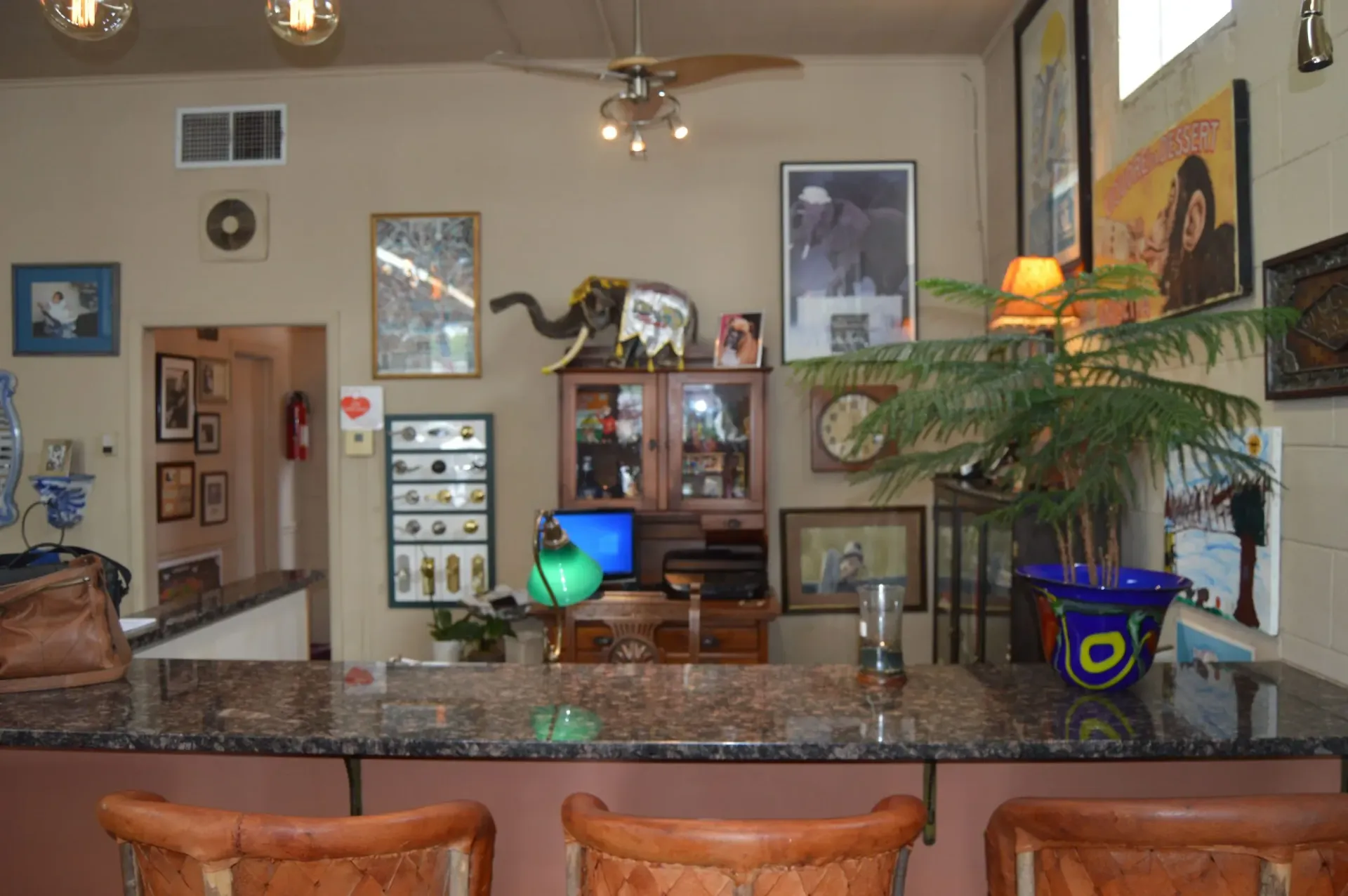 A kitchen with a bar and stools and a ceiling fan.