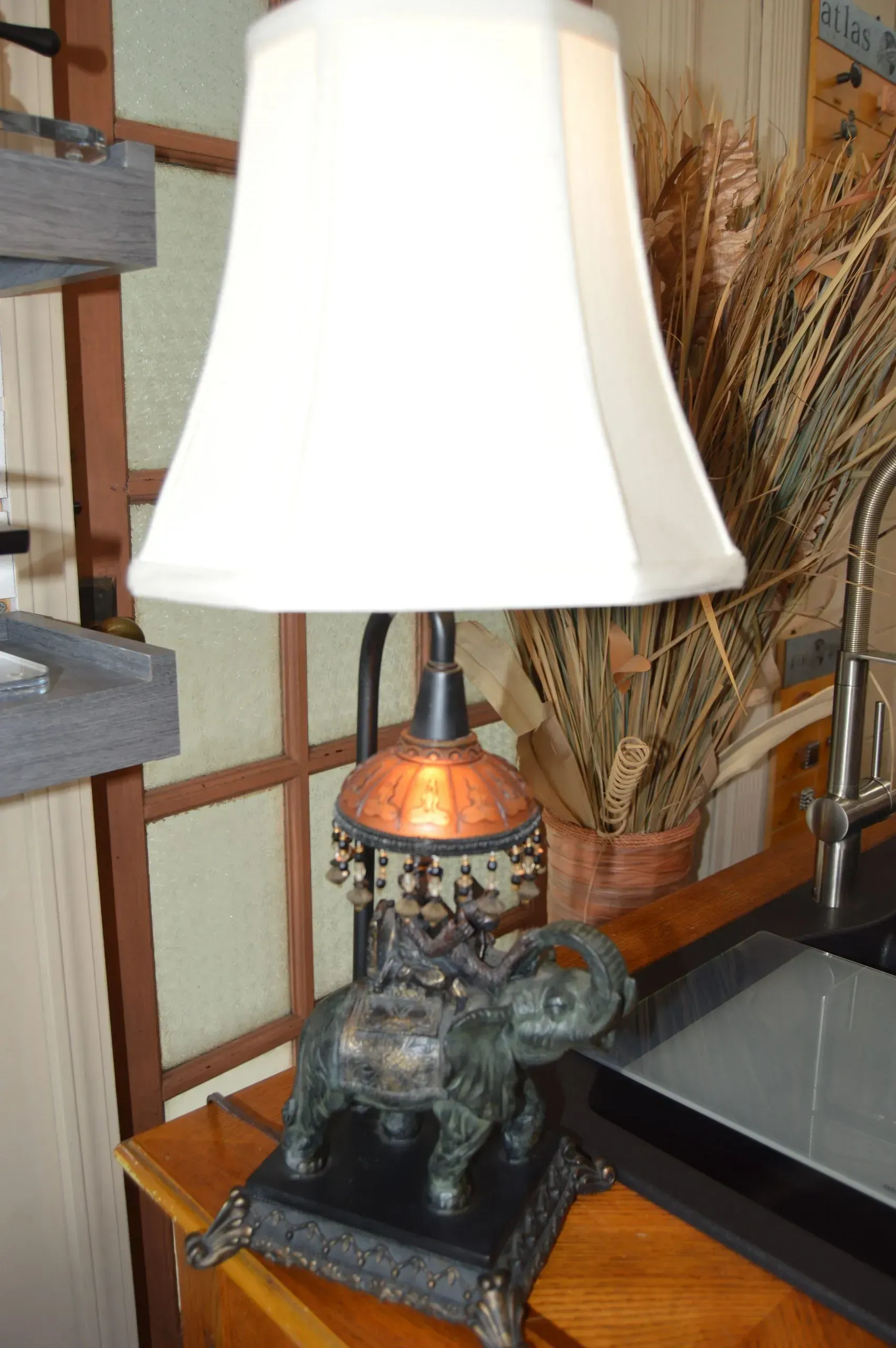 A lamp with a white shade sits on a wooden table