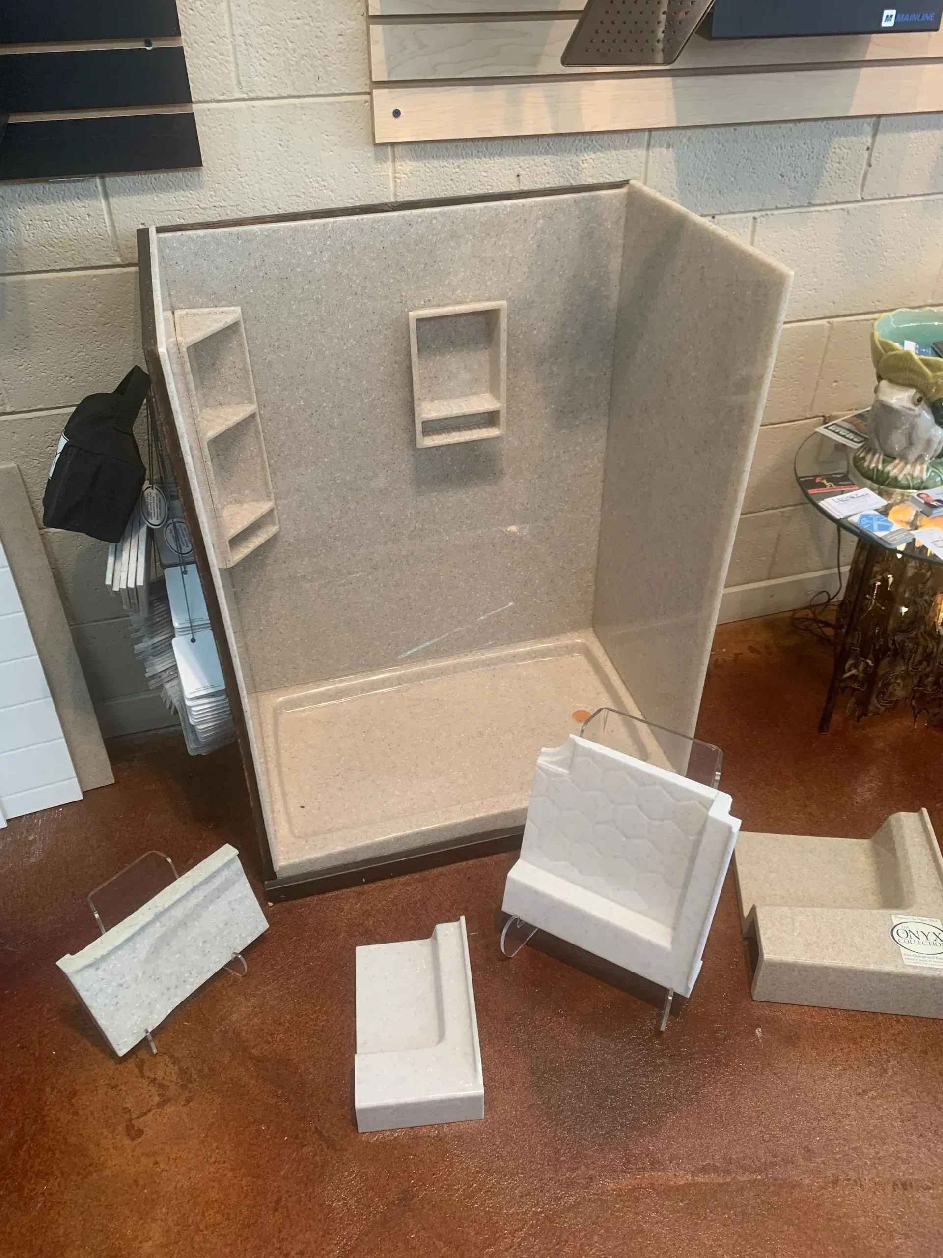 A shower stall is sitting on top of a wooden floor next to a brick wall.