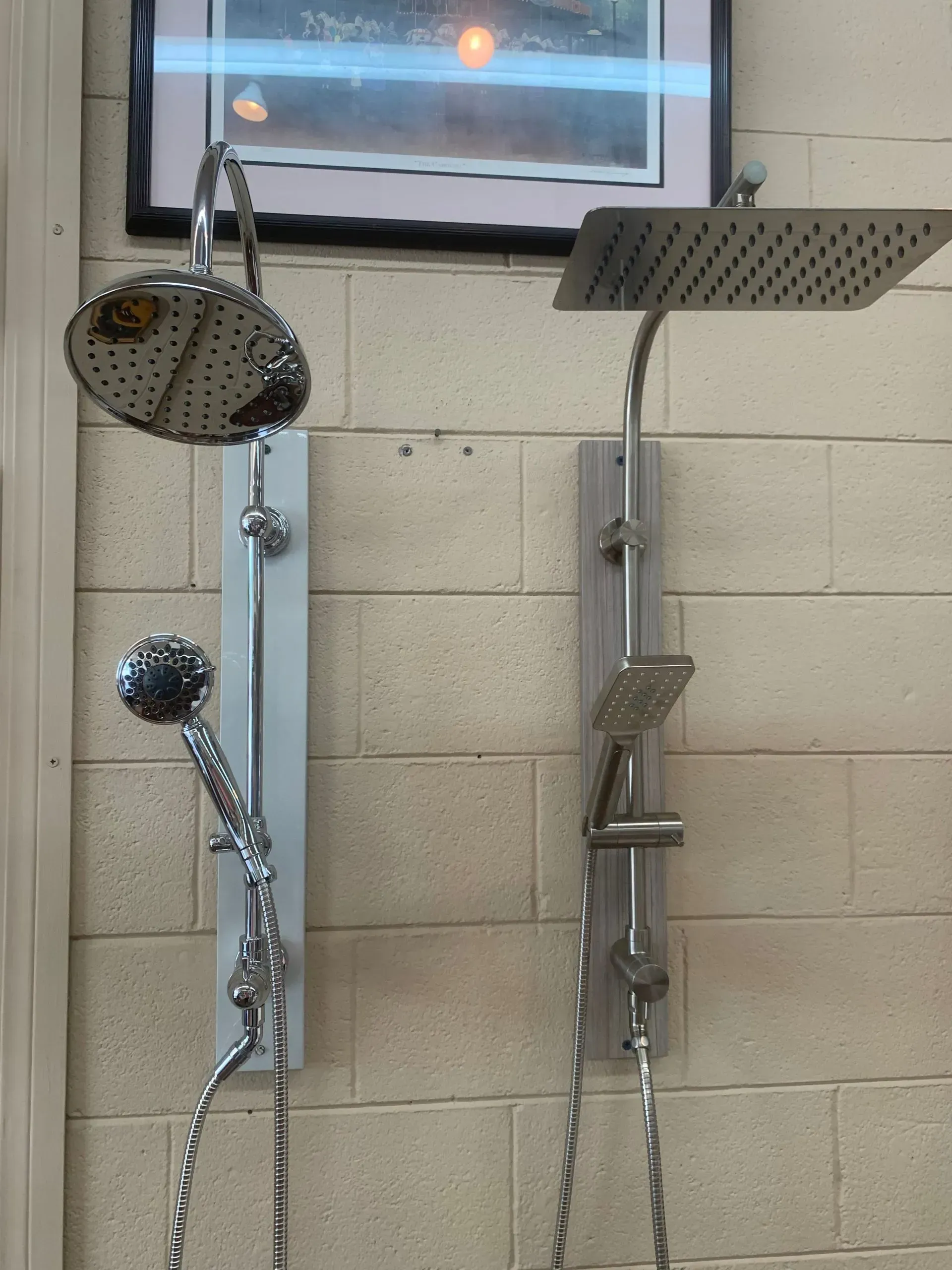 Two shower heads are hanging on a brick wall