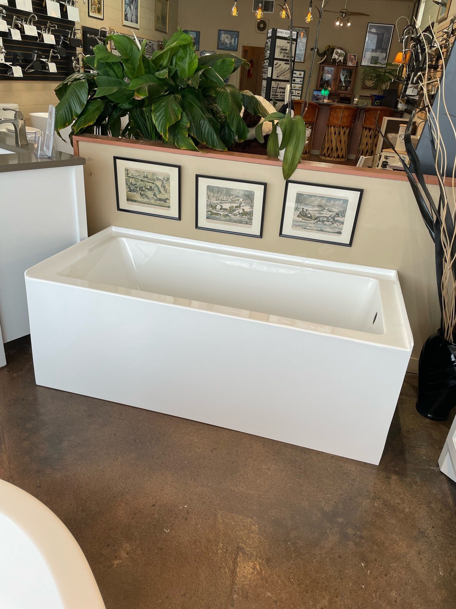 A white bathtub is sitting in a bathroom next to a plant.