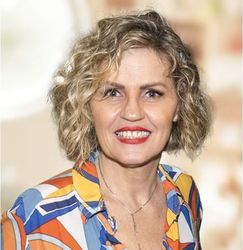 Uma mulher vestindo uma camisa colorida está sorrindo para a câmera