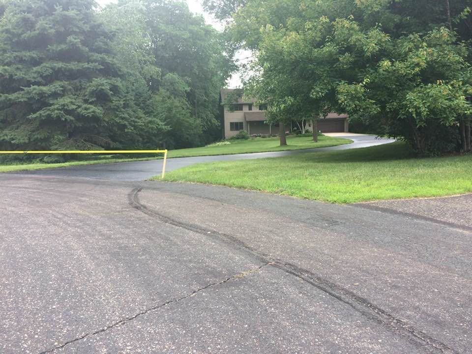 A driveway leading to a house surrounded by trees and grass.