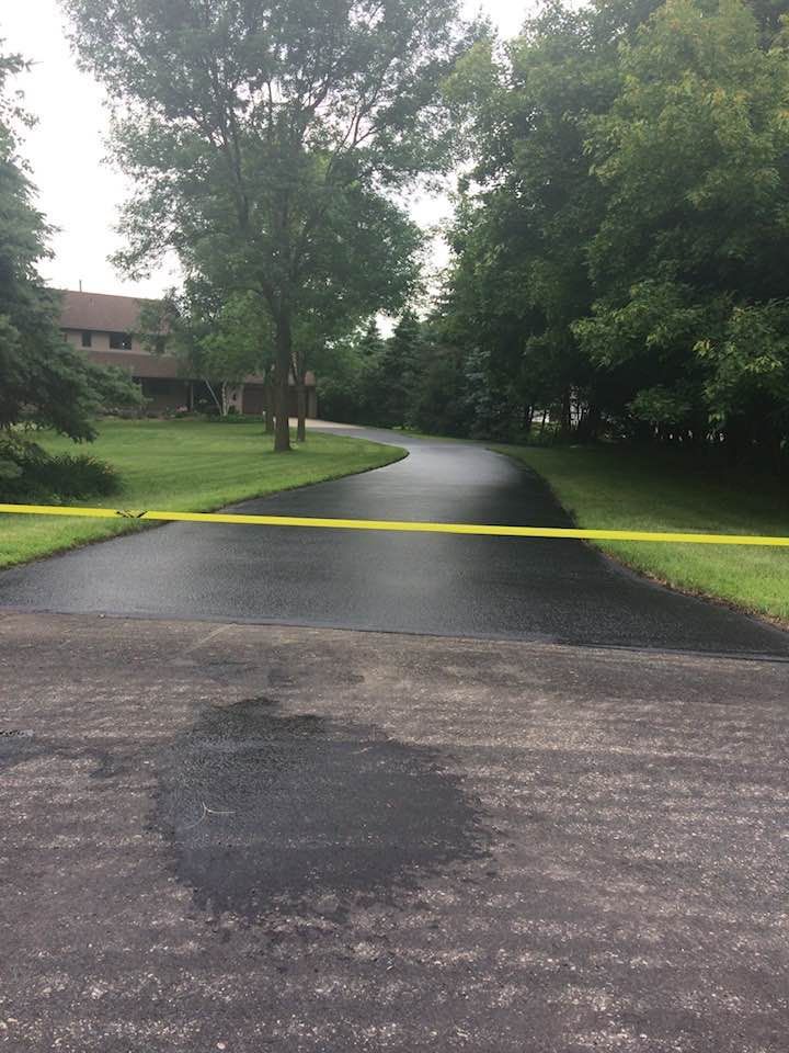 A residential driveway with a yellow tape on the side of it.