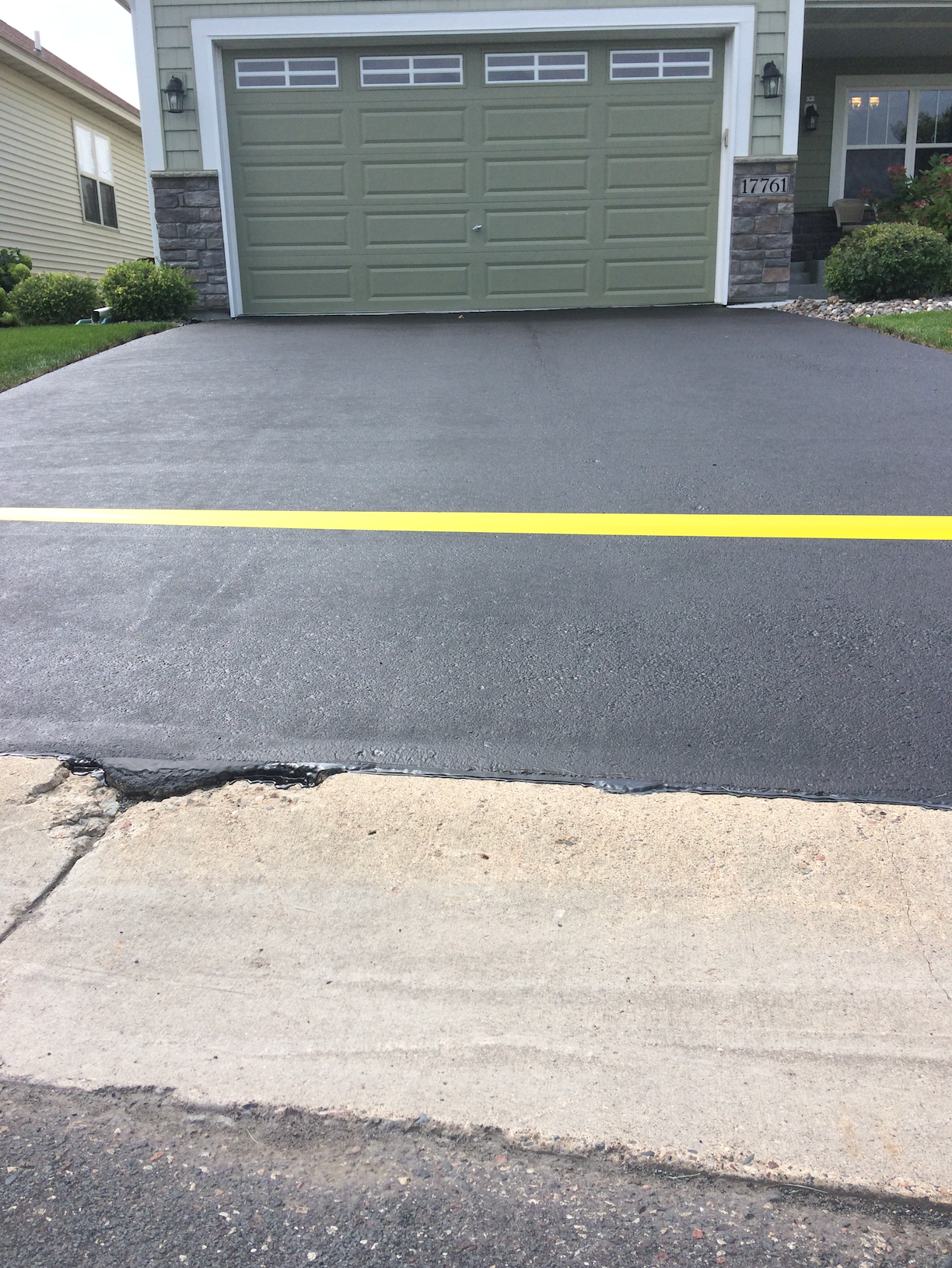 A black driveway with a yellow line in front of a house.