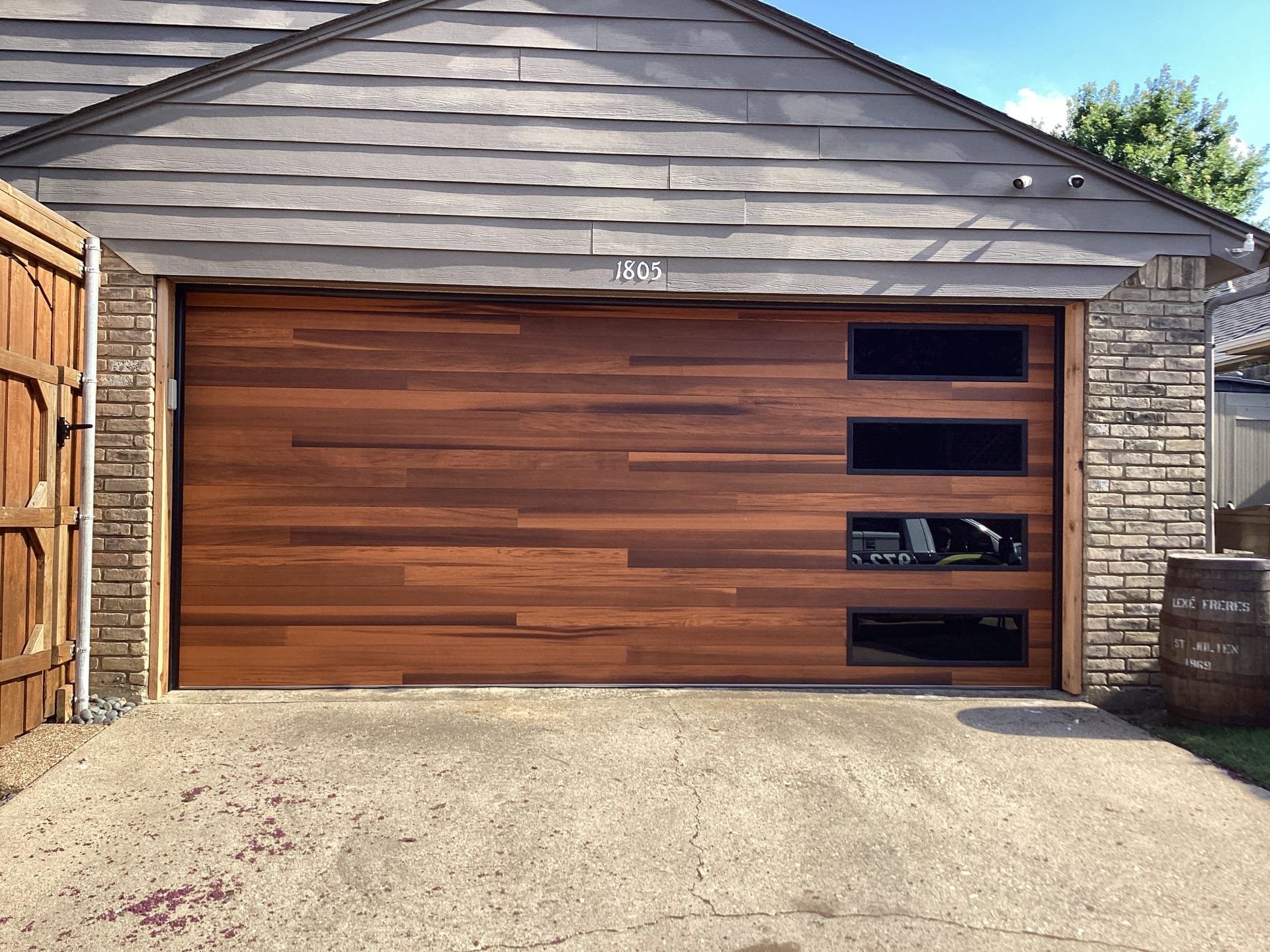 Wooden garage door with horizontal planks and rectangular windows. Concrete driveway.