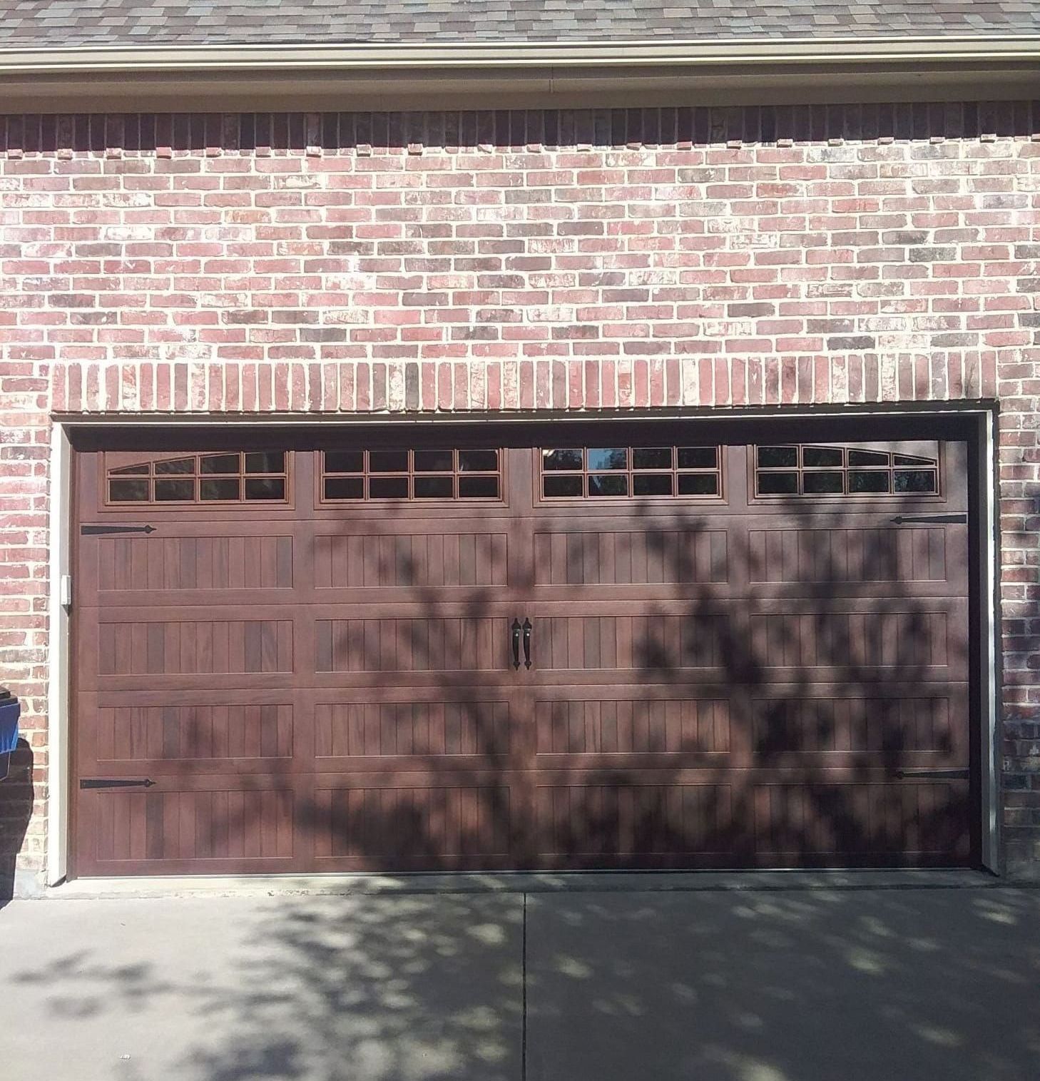 Brown garage door with windows, in a brick building.