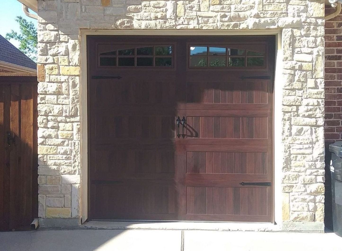 Brown garage door with windows, accented by a stone facade.