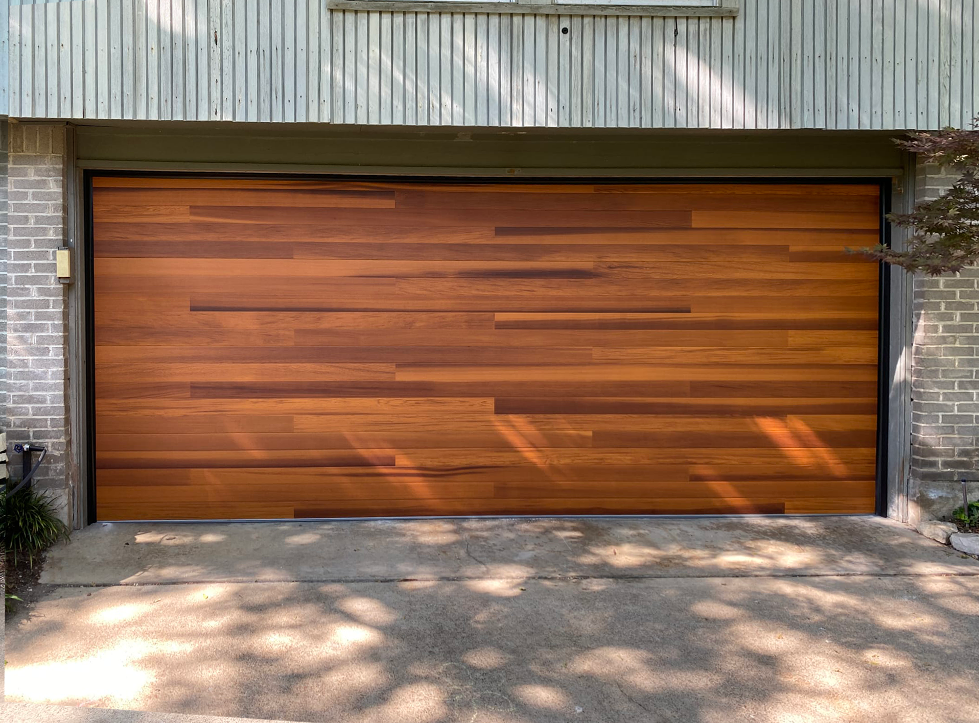 Wooden garage door with horizontal planks, set in a brick and wood-paneled building.