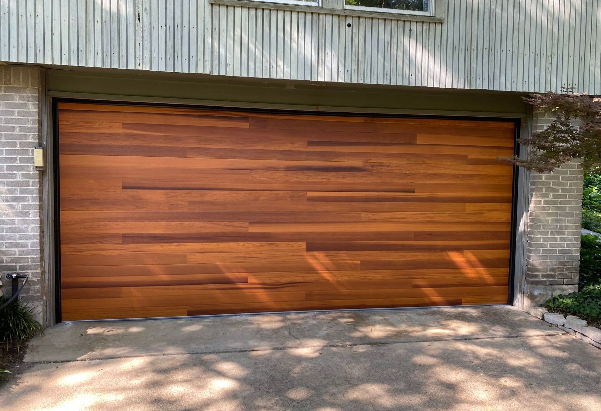 Wooden garage door with horizontal planks, set in a brick and wood-paneled building.
