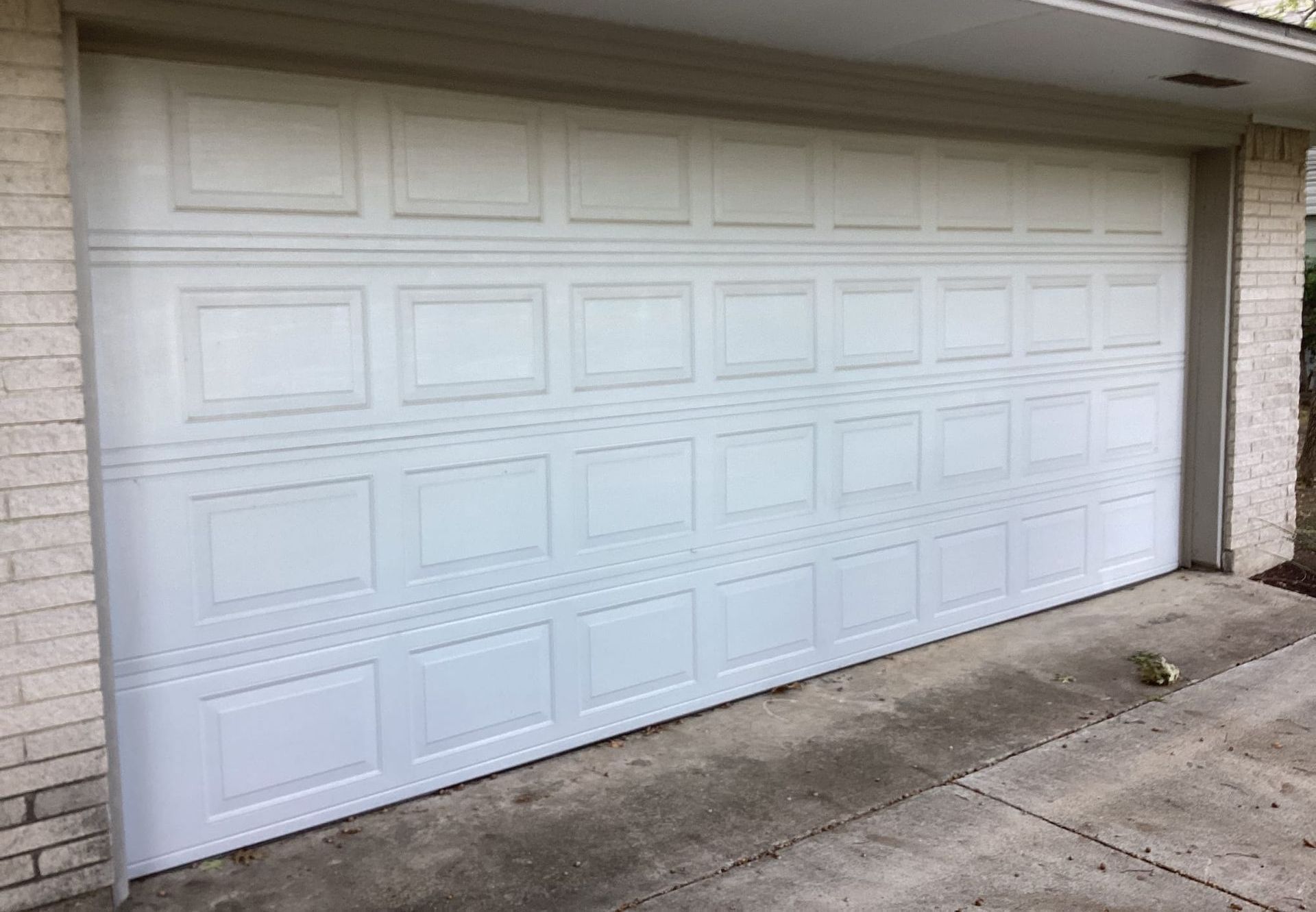 White panel garage door on a house with a concrete driveway and brick siding.