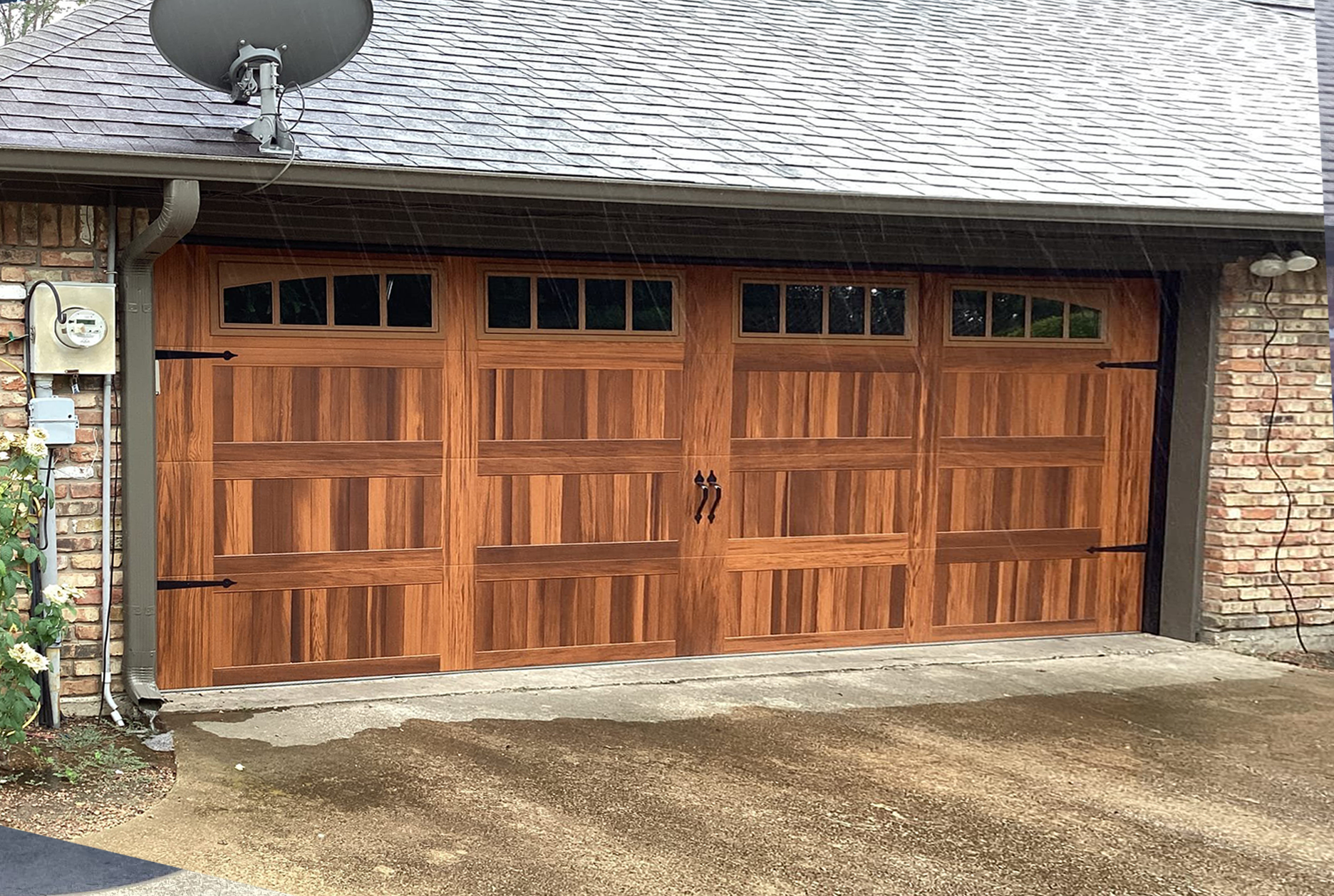 Wooden garage door with windows, brick exterior, and a power meter.