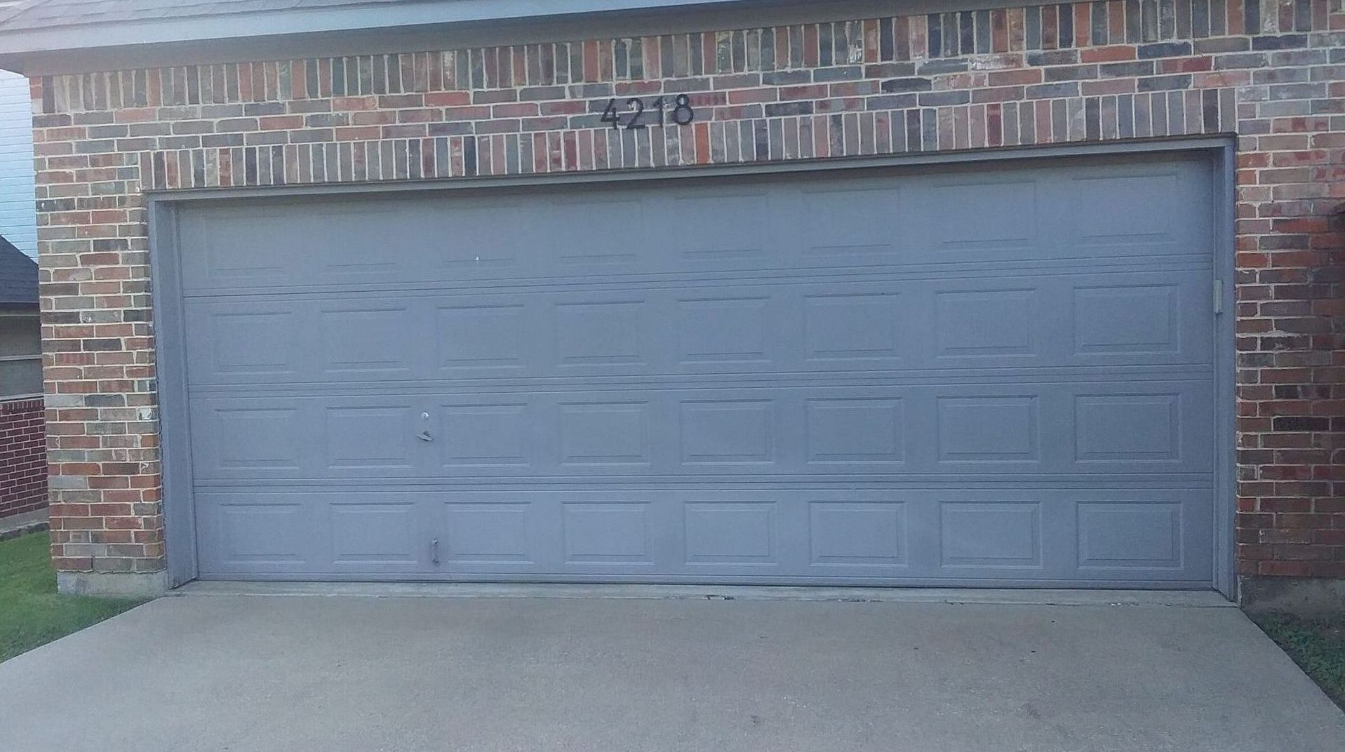 Gray garage door with address numbers 4213, brick exterior.