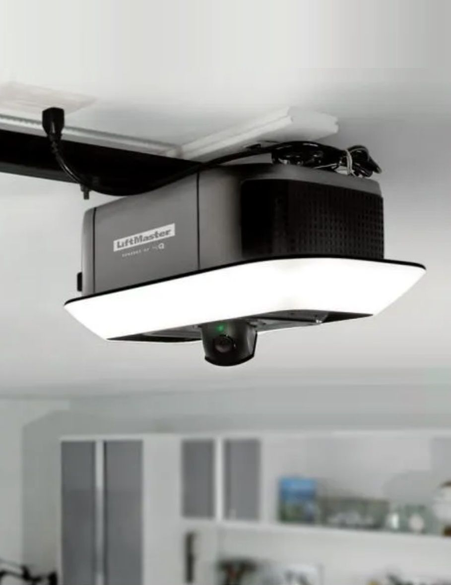 Garage door opener with built-in light and camera, mounted on a garage ceiling.