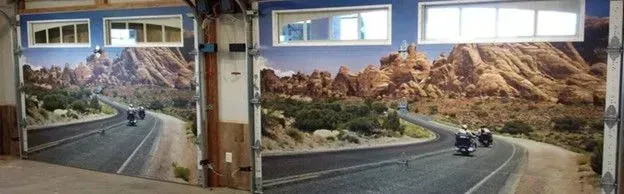 Garage doors painted with a desert road scene, motorcycles are driving on the road.