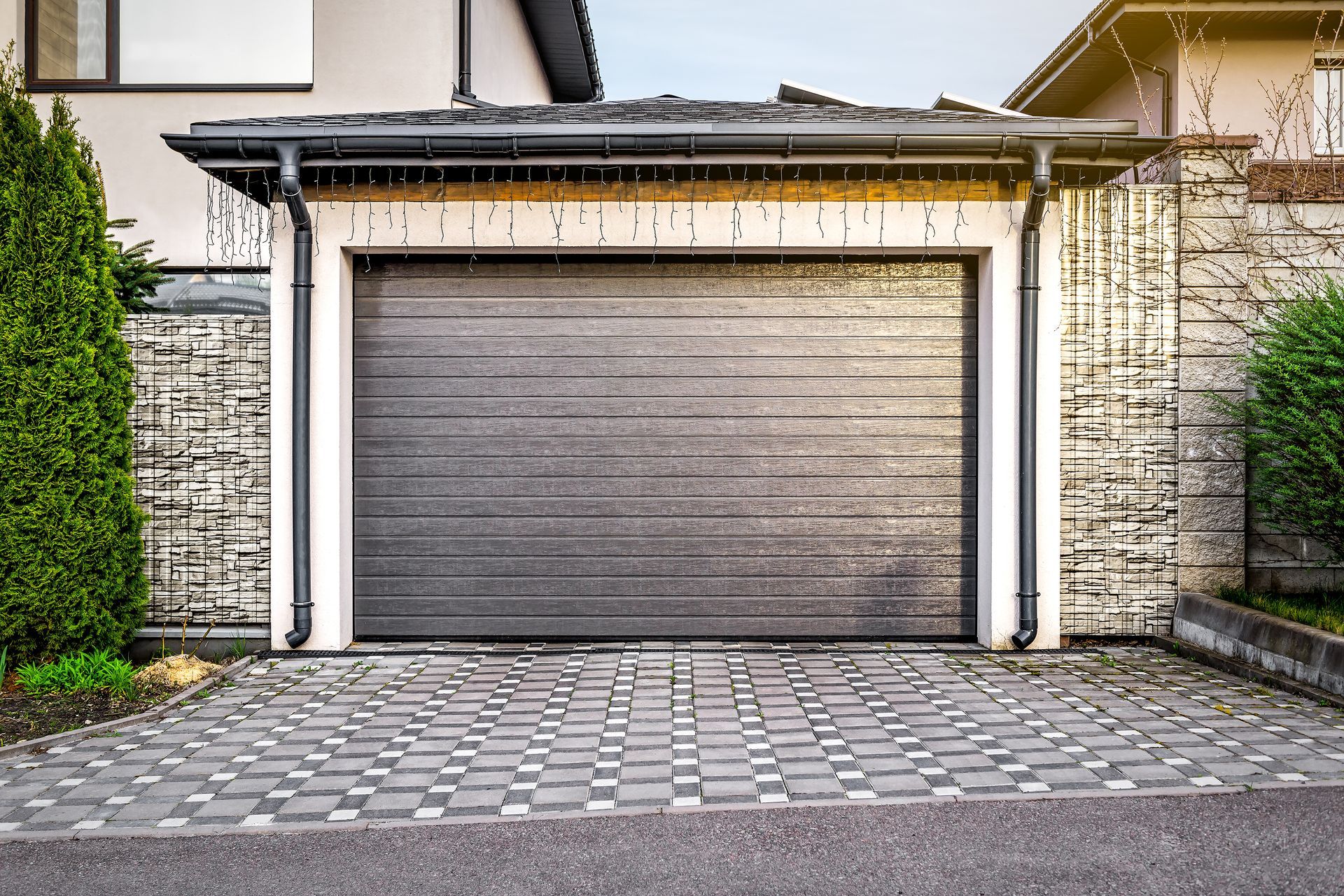 New garage door installation company installs charcoal steel sectional garage door with stone accent
