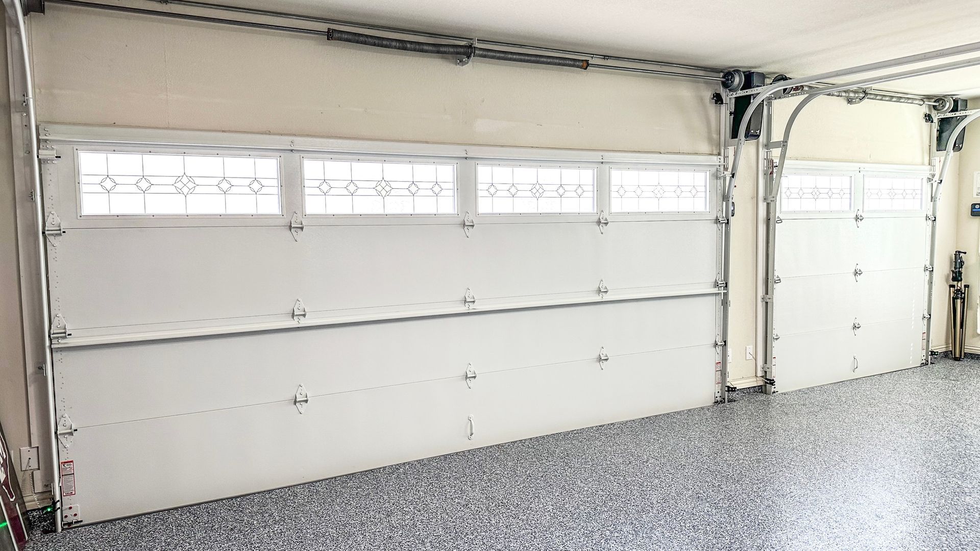 White garage doors with windows in a garage with a speckled floor.