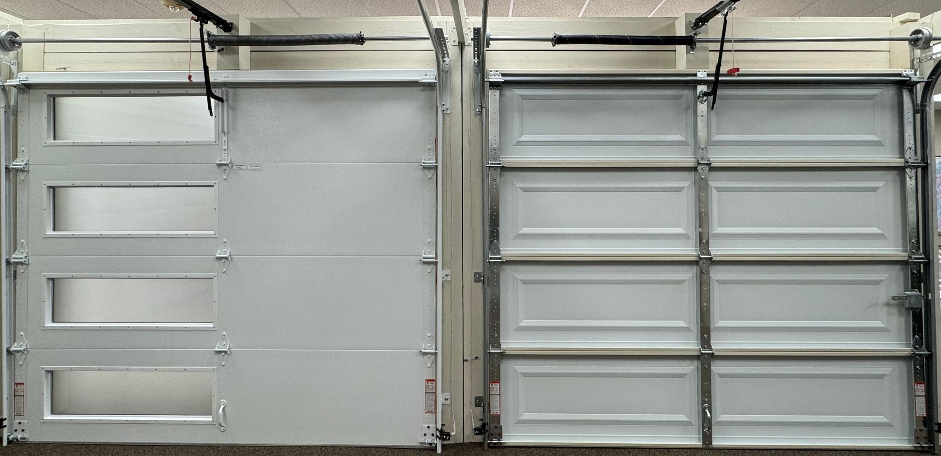 Two white garage doors side by side, one with windows and the other with panels.