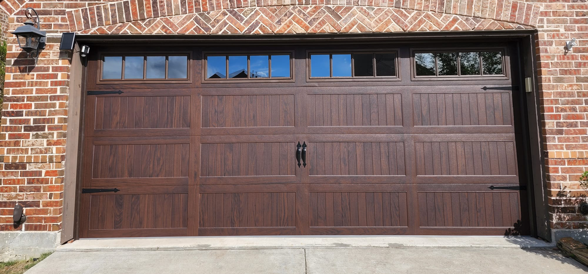 Brown garage door with windows against a brick building.