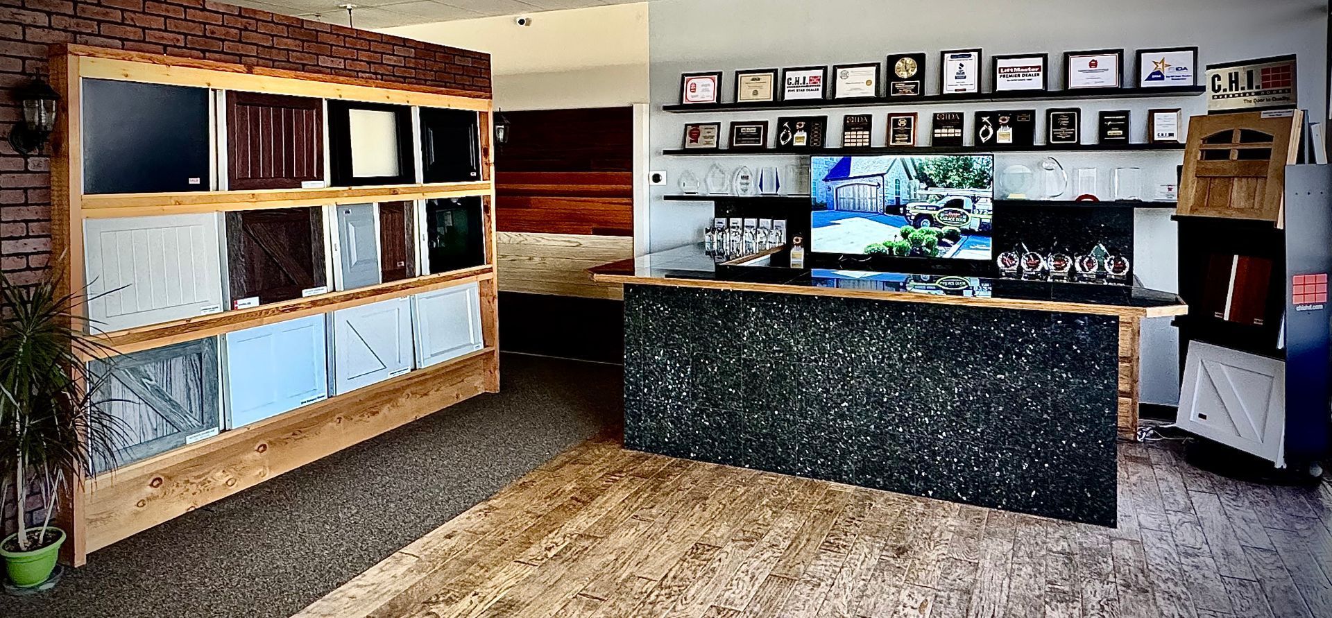 A display of building material samples and a counter with a TV and fireplace against a wall with pictures.