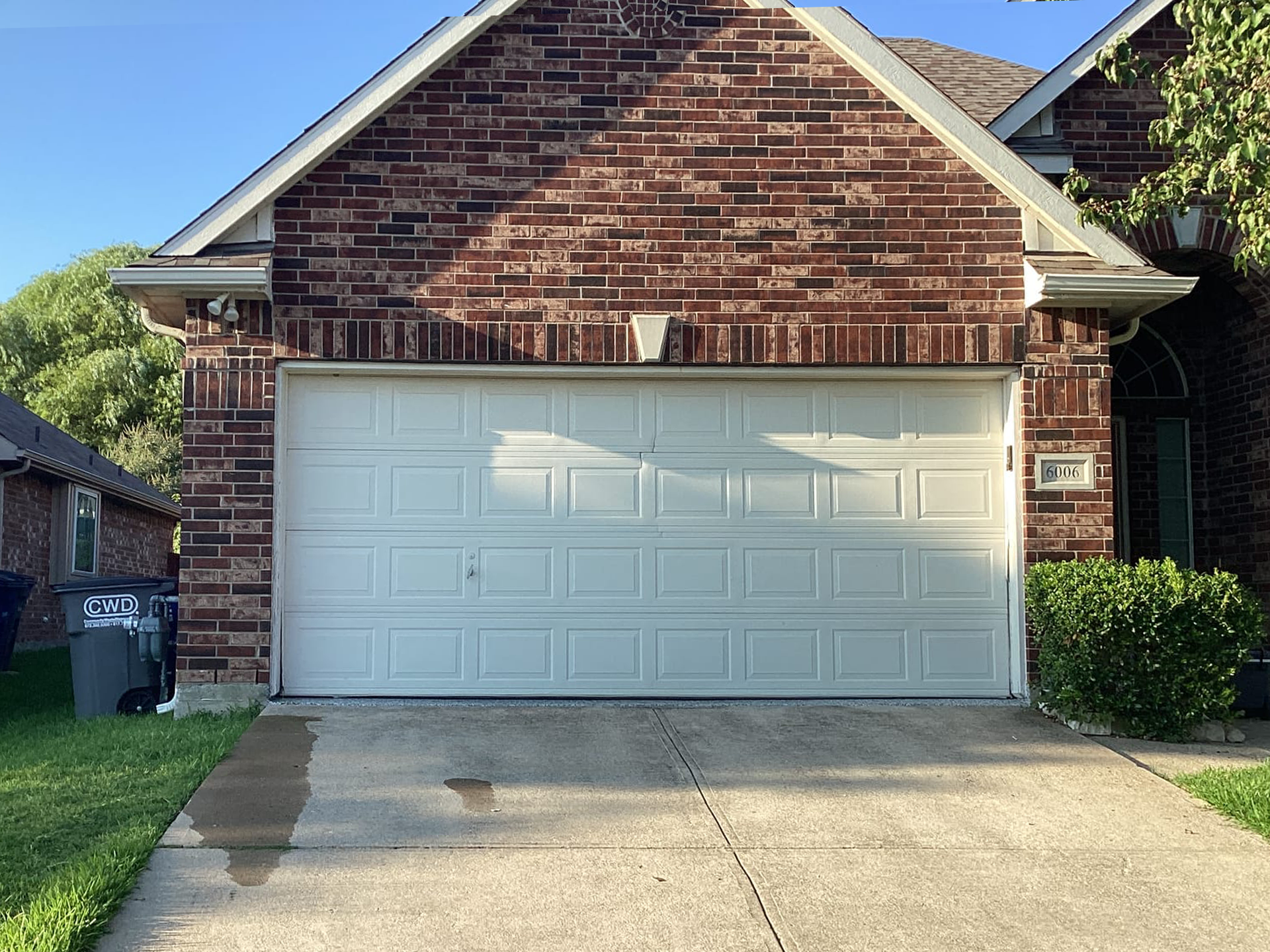 White garage door on brick house with concrete driveway.