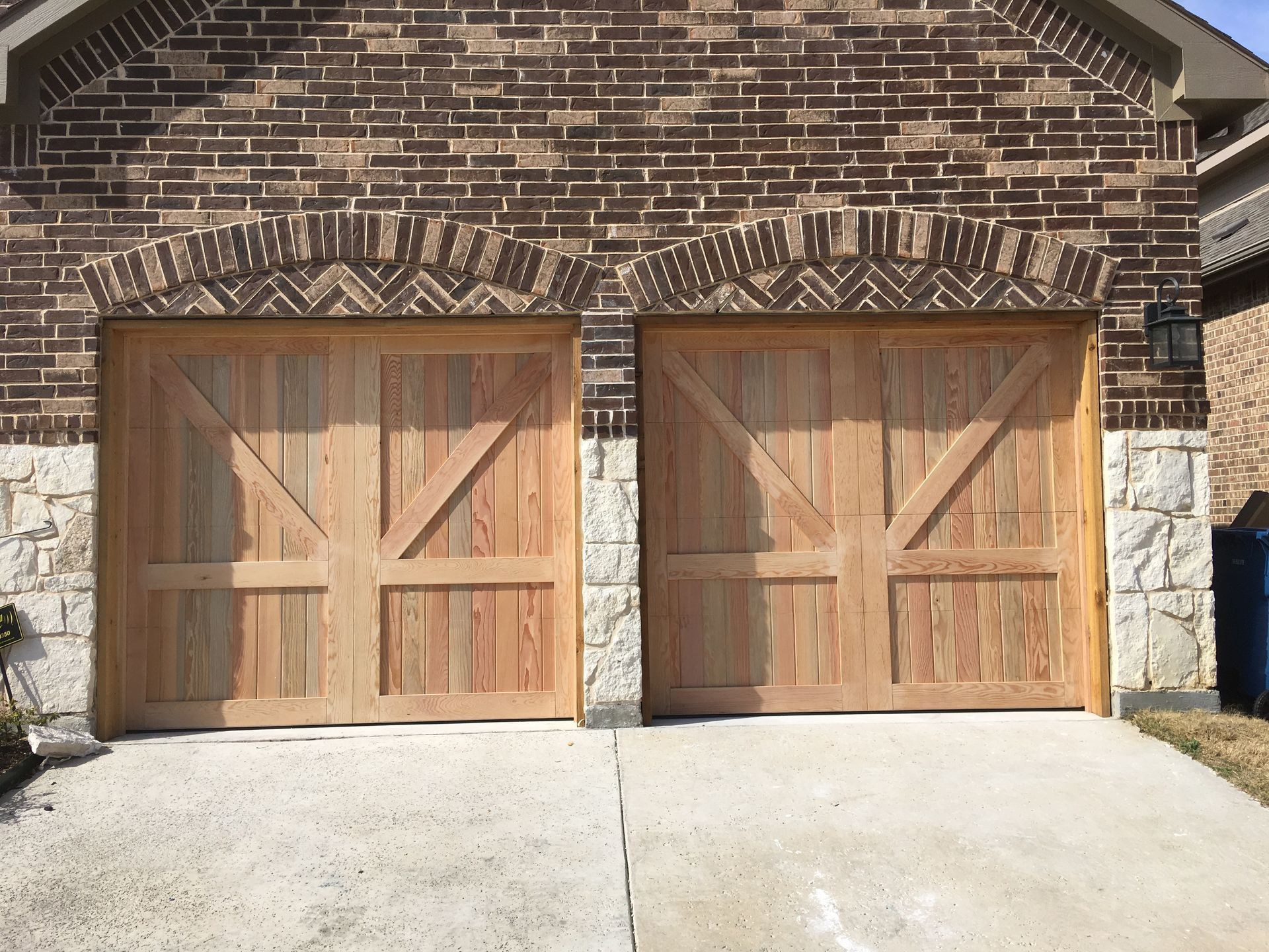 Two wood-paneled carriage-style garage doors set into a brick and stone facade.