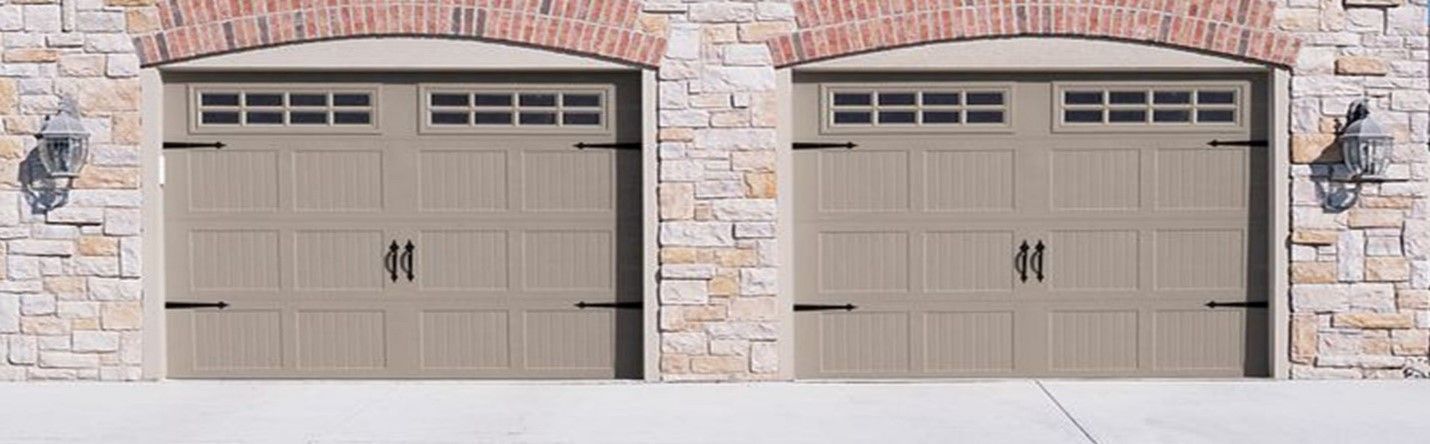 Two beige garage doors with stone accents and arched brickwork.