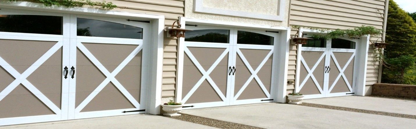 Three garage doors with brown panels, white crisscross accents, and a stone driveway.