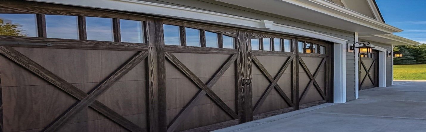 Brown wooden garage doors with cross design and glass windows, exterior view.