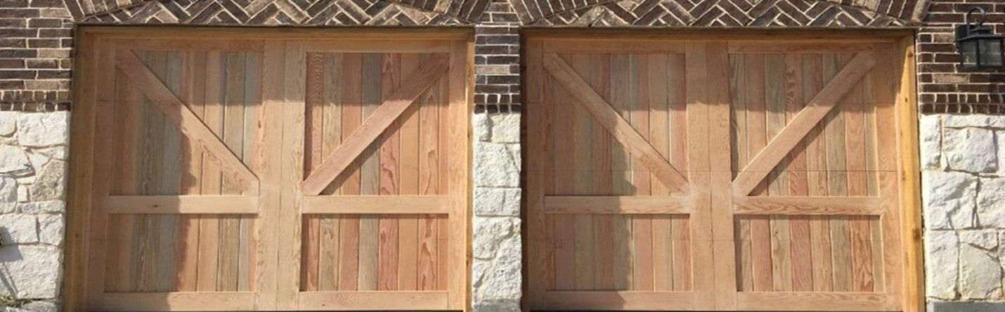 Two wooden garage doors with cross-shaped design. Brick and stone wall in the background.