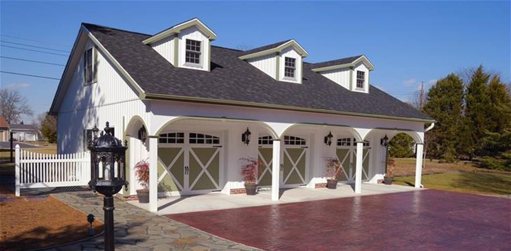 A detached white three-car garage with three dormer windows, arched covered entryways, and a dark shingled roof.