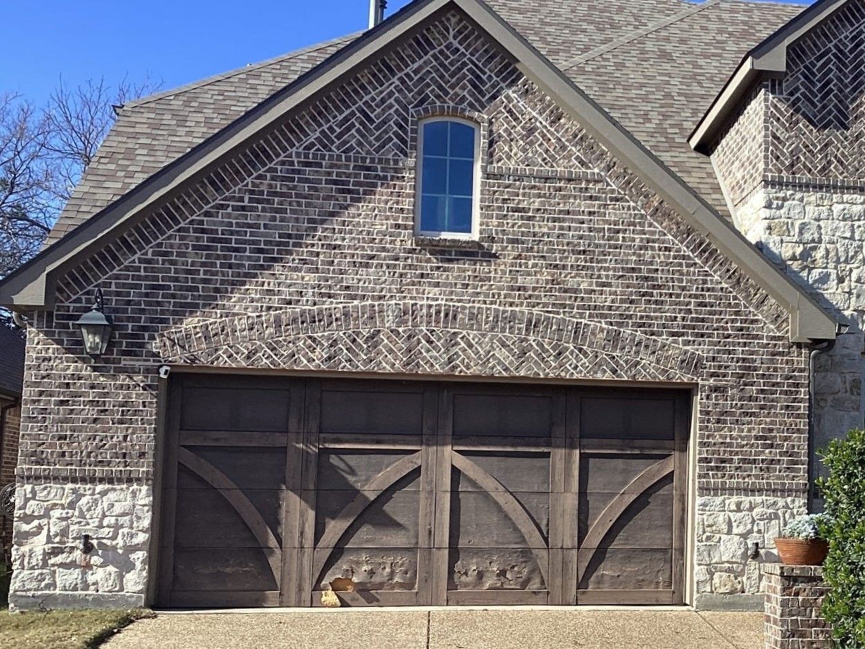 Garage with dark wood door and brick facade, light stone accents.