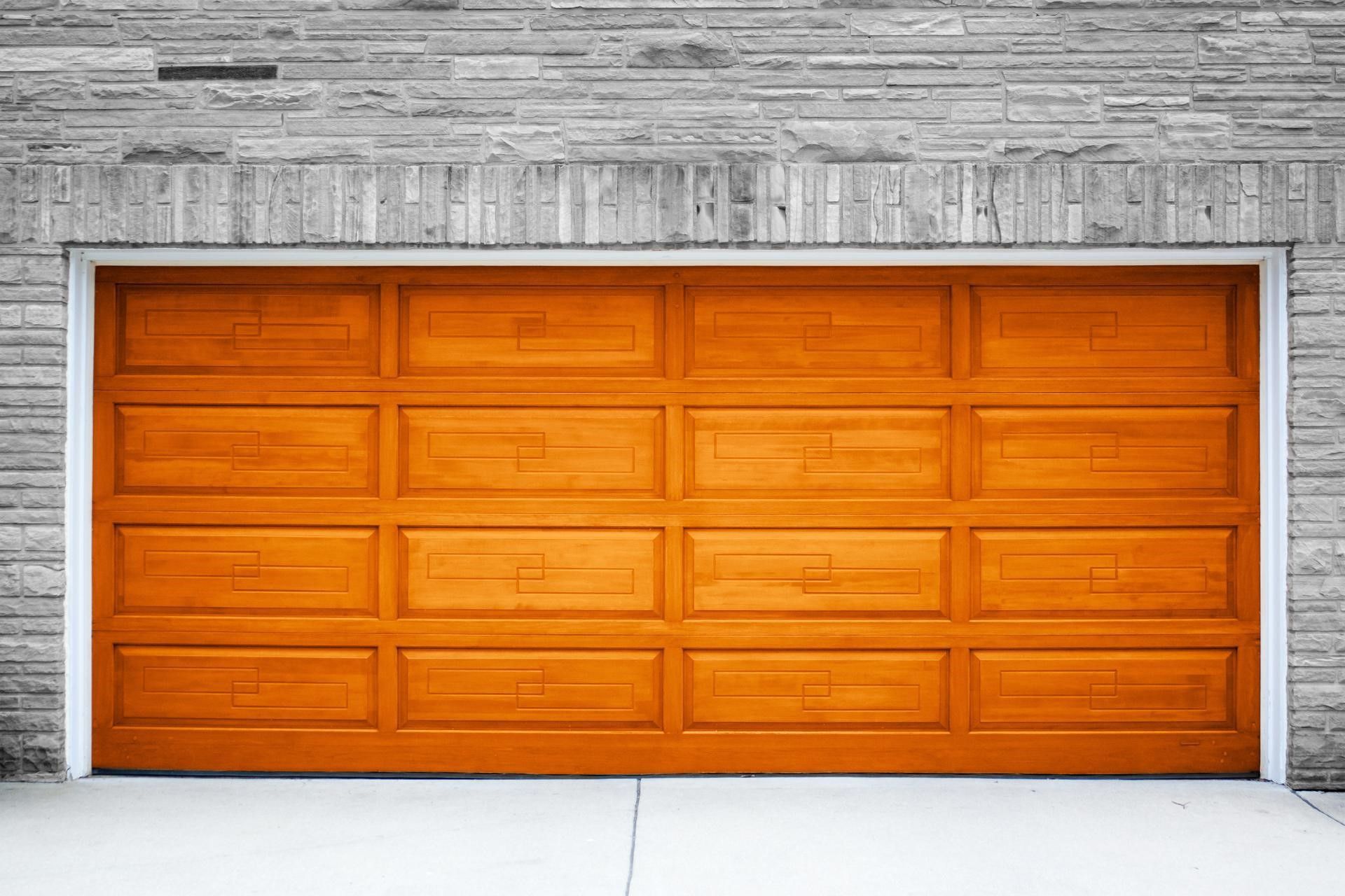 Orange wooden garage door with a concrete floor and a gray brick wall.
