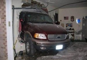 Maroon SUV crashed into a garage, destroying the wall and door.
