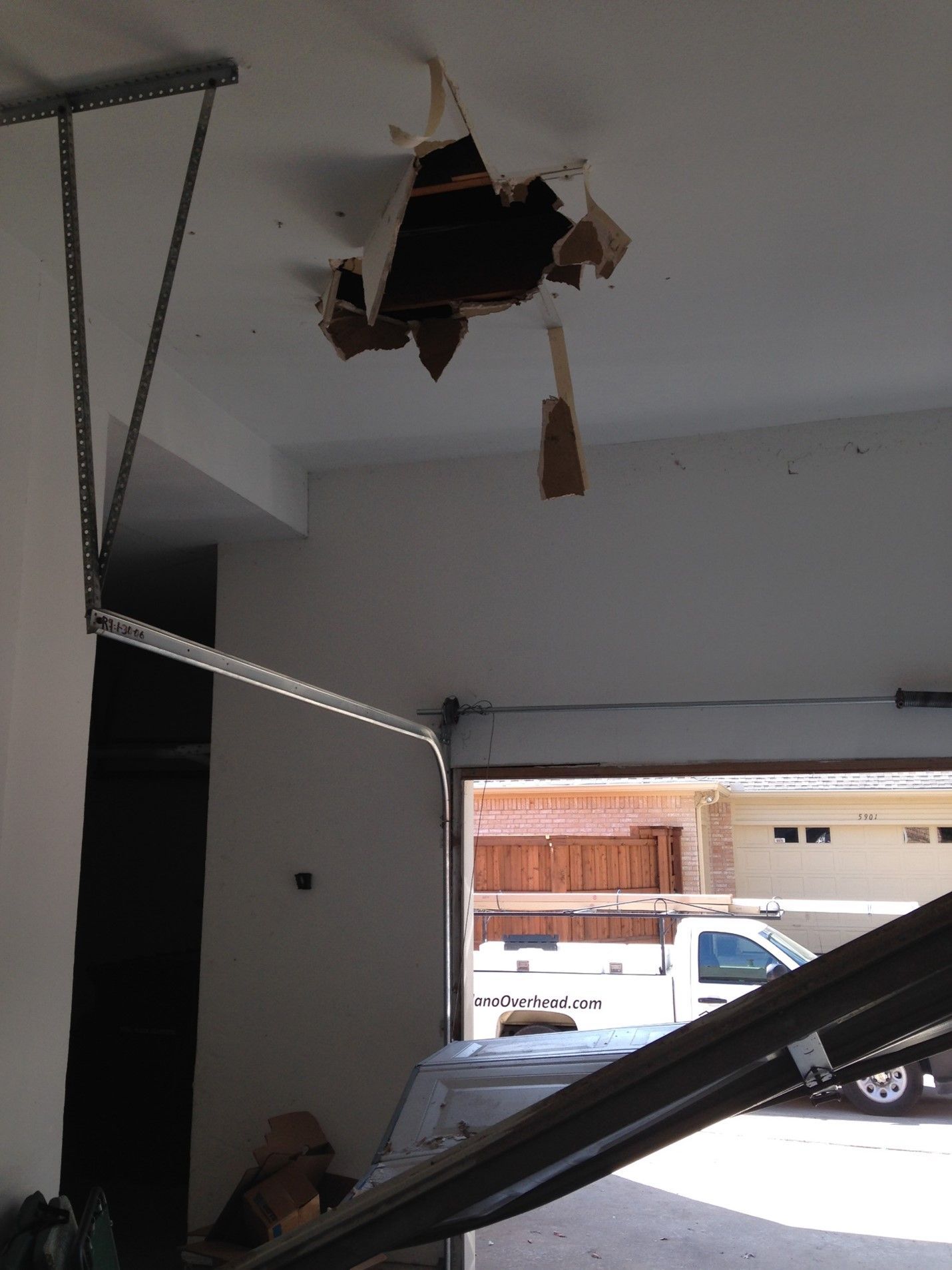 Garage ceiling with a large hole. The garage door is open, with a car visible outside.