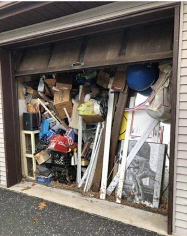 Garage crammed with various boxes, objects, and debris, partially blocking the opening.