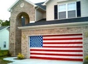 Garage door painted as the American flag on a brick house.