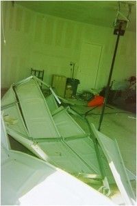 Collapsed white framed tent inside a room with unfinished walls. A black pole stands upright.
