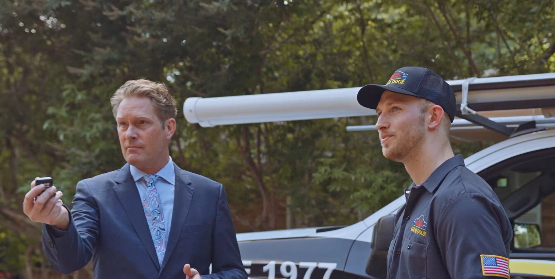 Man holding a remote control to operate a closed garage door.