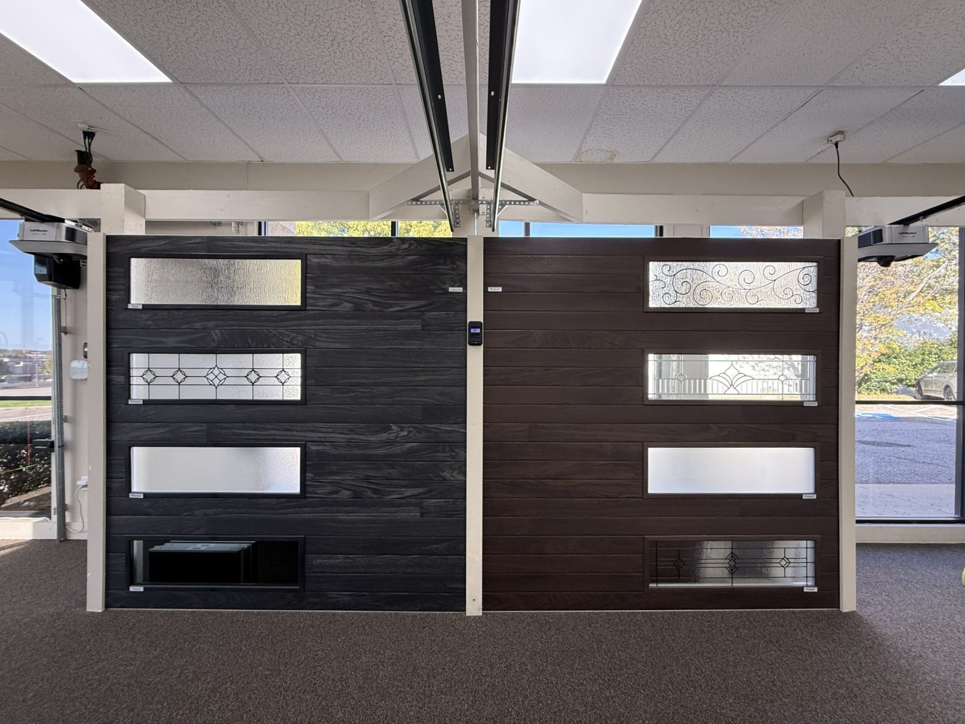 Two garage doors: dark wood grain with windows, displayed in a showroom with open automatic openers.