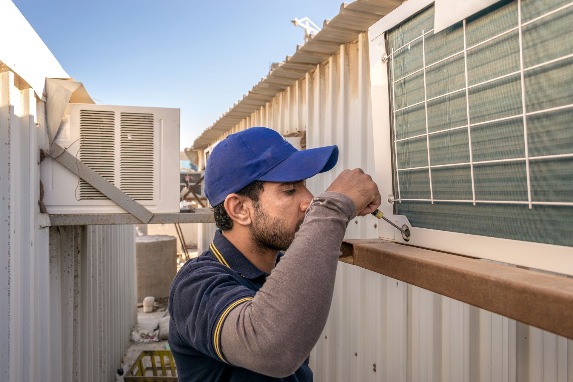 a Person in a Blue Cap, Repairs an Ac Unit — Don Hall Air Conditioning & Electrical in Smithfield, QLD