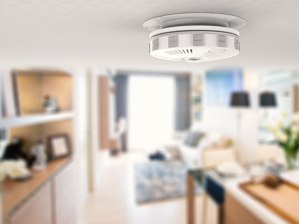 Smoke detector mounted on a white ceiling, in a blurred interior.— Don Hall Air Conditioning & Electrical in Smithfield, QLD